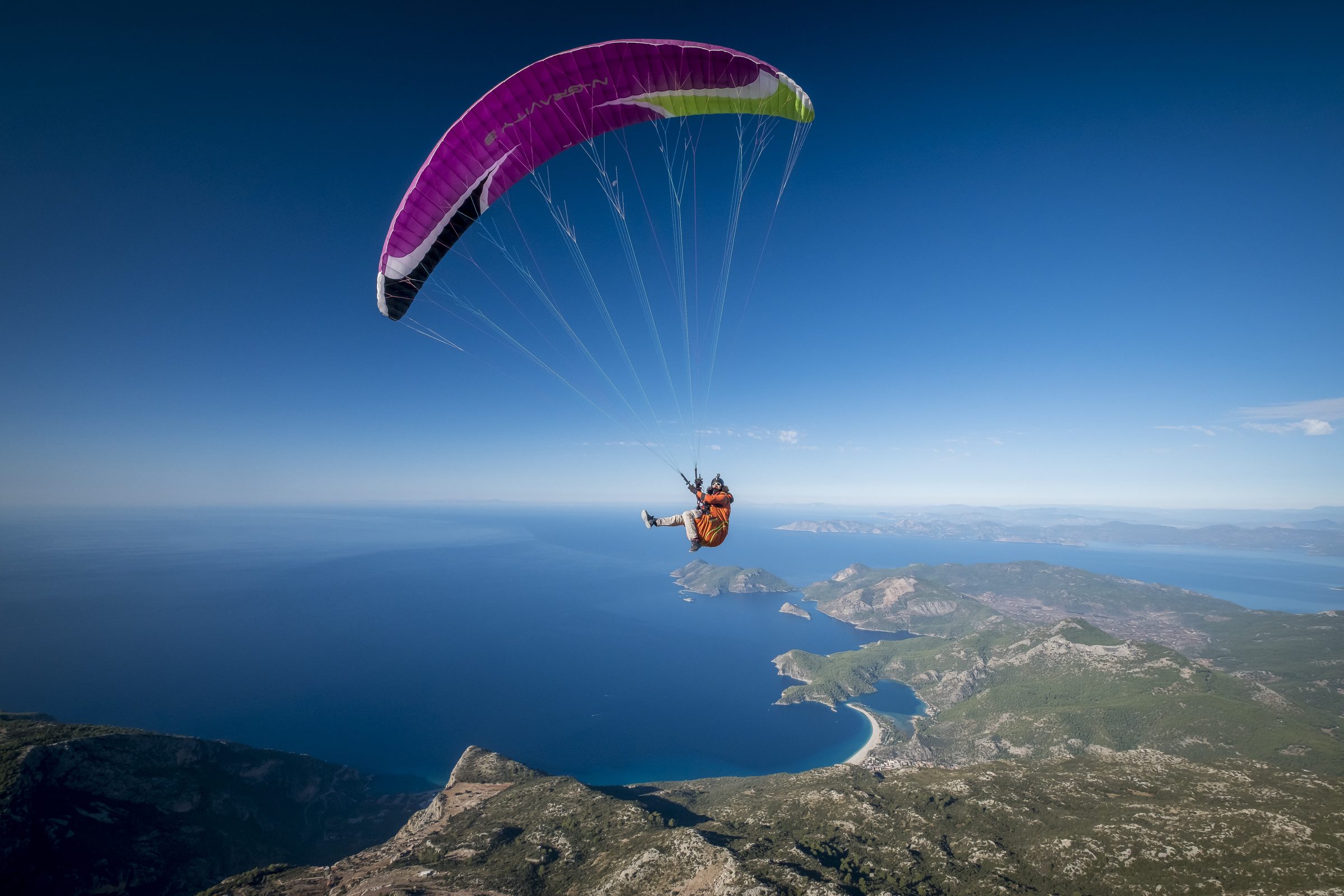 Ölüdeniz üzerinde mor kanatla süzülen pilot